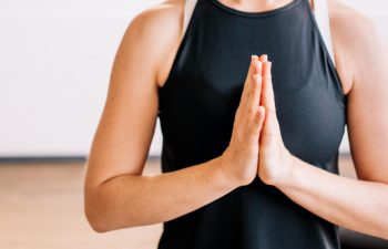 meditating young woman with hands put together in front of her chest