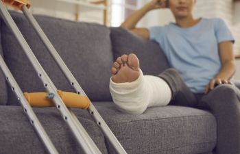 A person with an injured leg in a cast resting on a sofa.