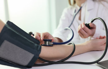 Zapisz Podgląd pobierania Doctor uses sphygmomanometer with stethoscope to check blood pressure of patient